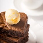 Brownie with ice cream and a cup of coffee on the table vertical