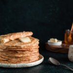 Stack of traditional russian pancakes blini on black background with copy space. Homemade russian thin pancakes blini. Russian food, russian kitchen
